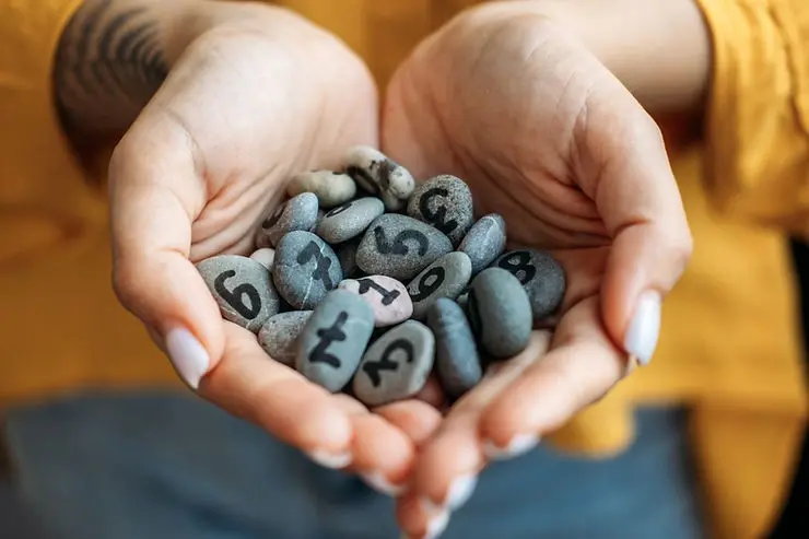 Numbered stones in hands representing different feedback scales used for employee surveys and evaluations.
